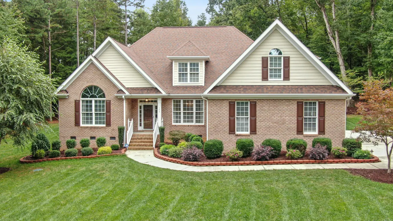 Maintained lawn with metal-edged bark and river rock beds at a residential property